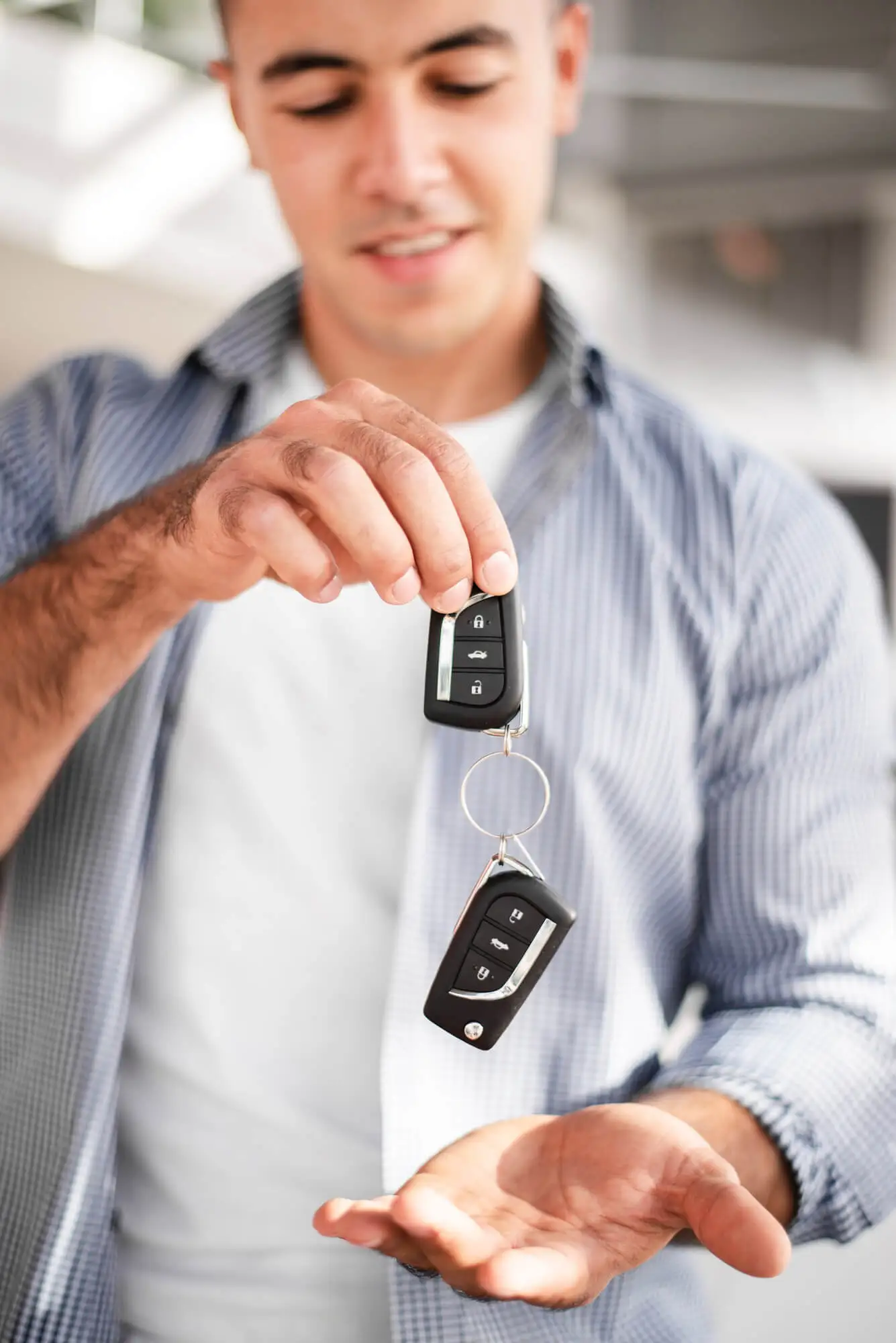 Smiling man showing two remote key fobs – key programming and duplication