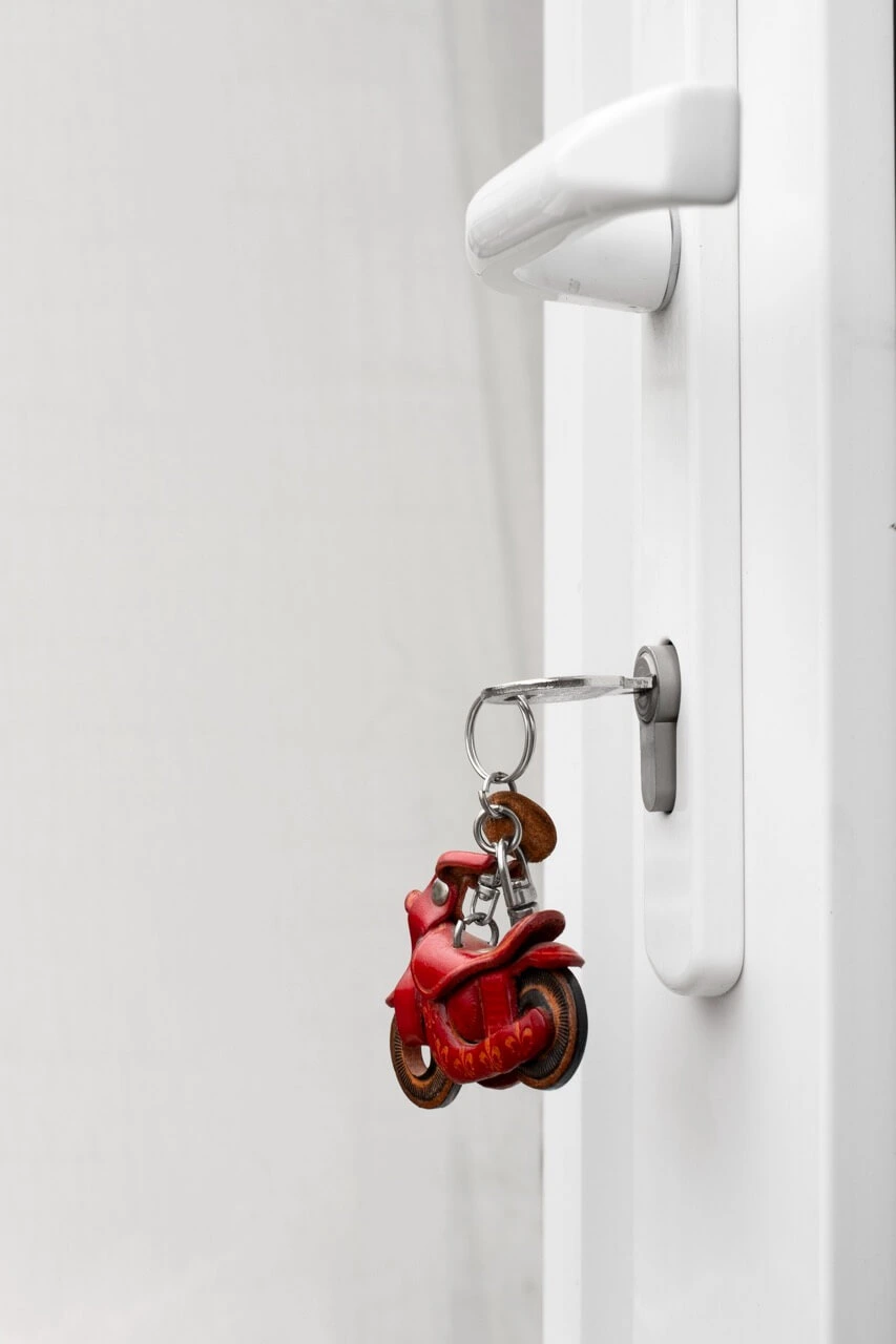White door handle with inserted key and red motorcycle keychain