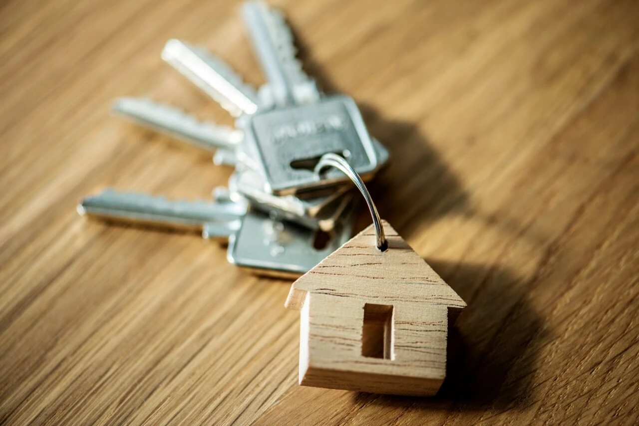 Keyring with multiple house keys and wooden home-shaped keychain on wooden surface