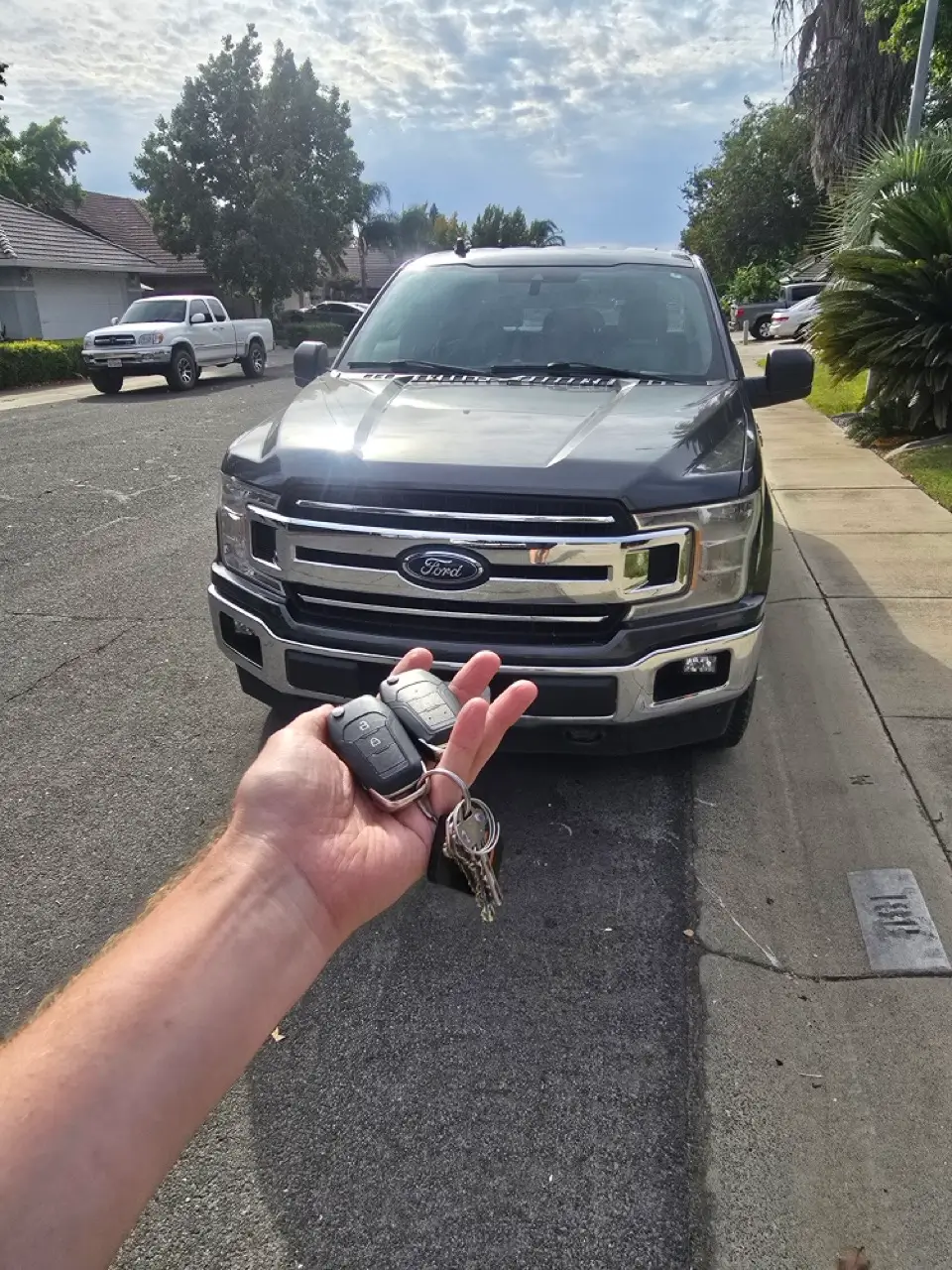 Locksmith technician programming a new Ford car key and remote for key replacement service.