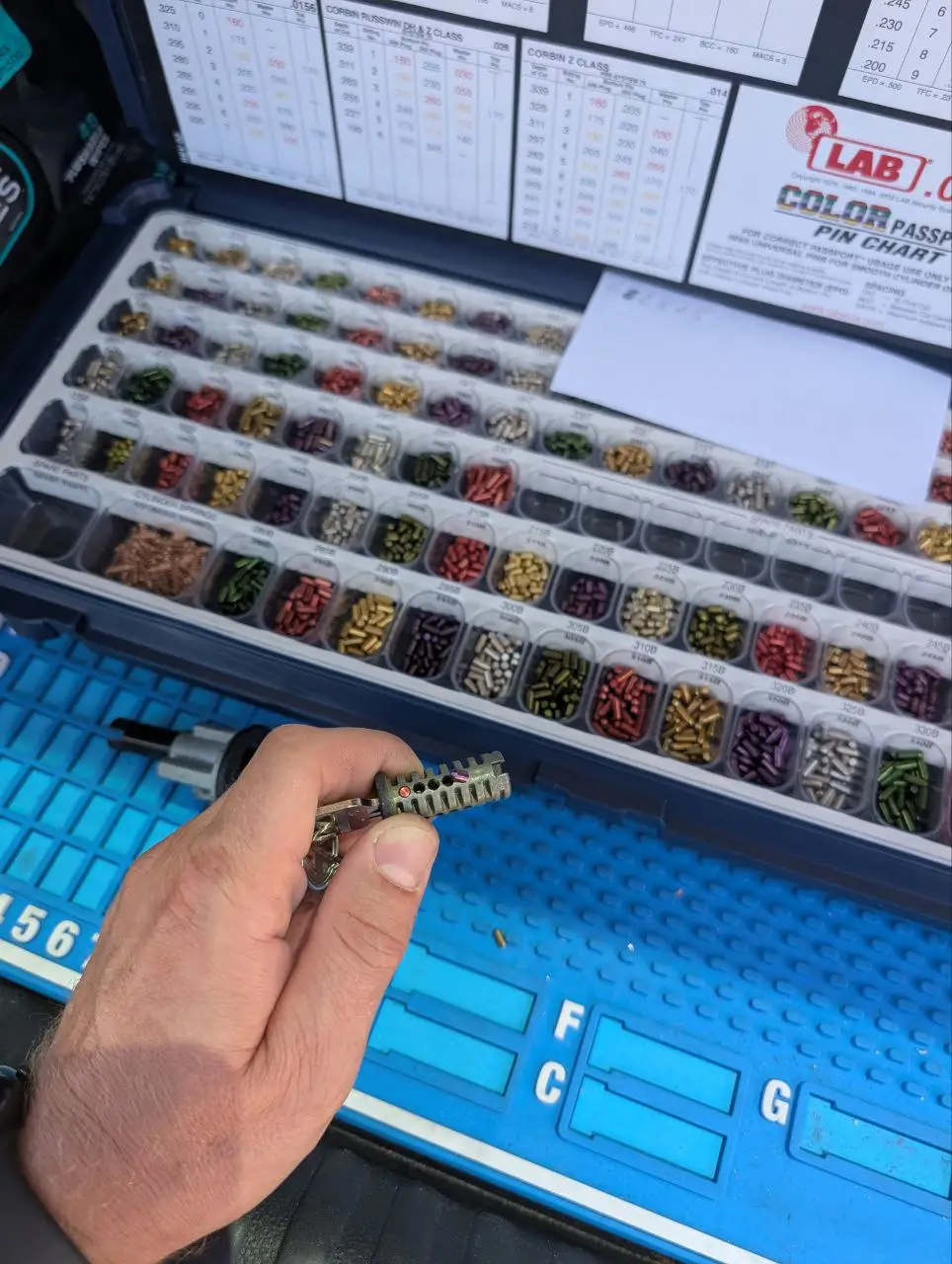 Locksmith rekeying a lock cylinder using a color-coded pin kit.